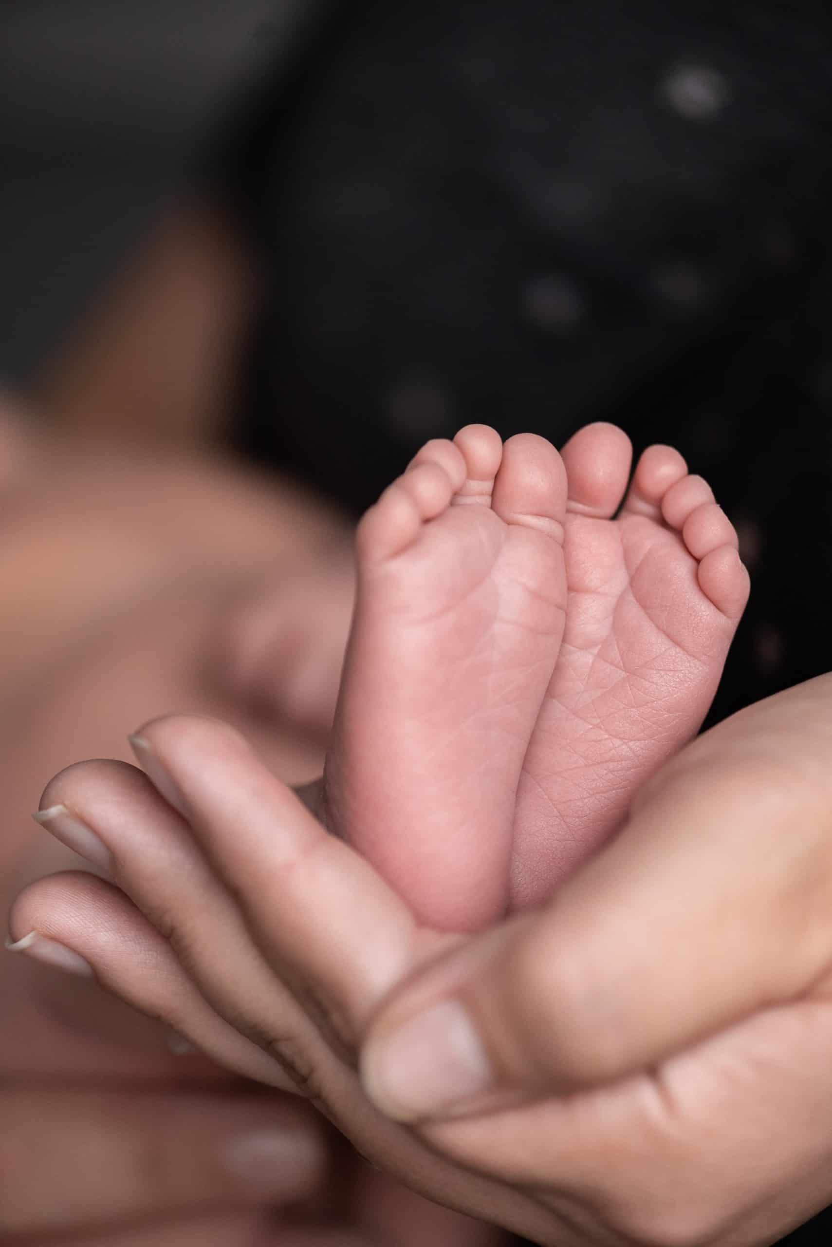 newborn photo of the baby's feet being held by her mum