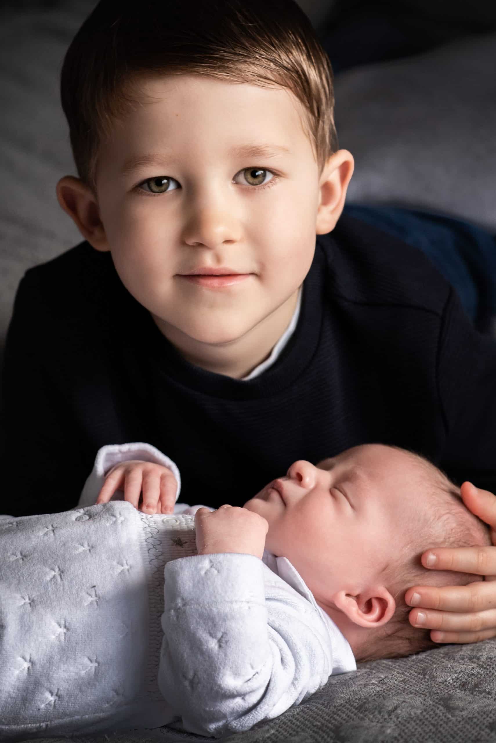 Brig brother have his portraits taken whilst cuddling his newborn baby brothers